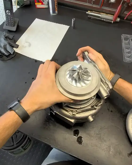 Hands fitting a turbo’s rotating assembly into its housing