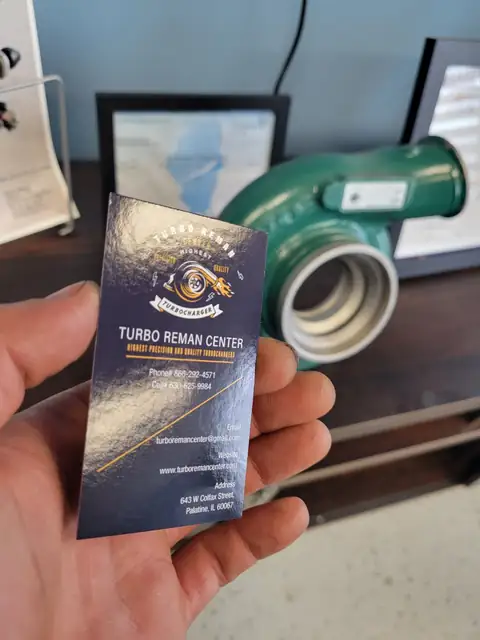 Turbo Reman Center business card held in front of a turbo housing